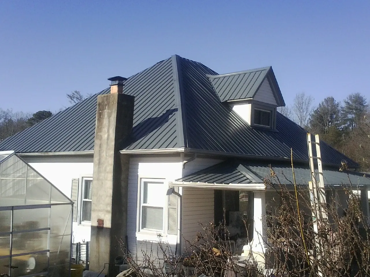 Dark blue standing seam metal roof on a white farmhouse with dormer — Slate & Tile Roof Repair by Roofing Brothers in Soledad