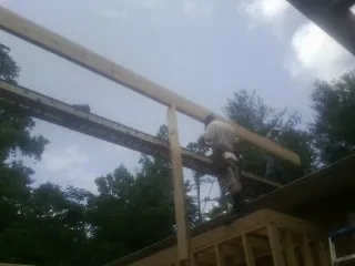 Carpenter setting a ridge beam over a new addition frame — Ice Dam Removal by Roofing Brothers in Soledad