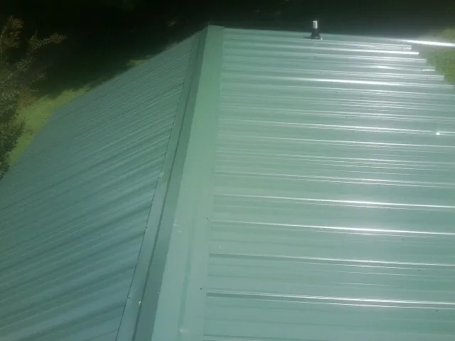 New green metal panels meeting at the ridge of a roof — Flat Roof Repair work by our crew in Soledad