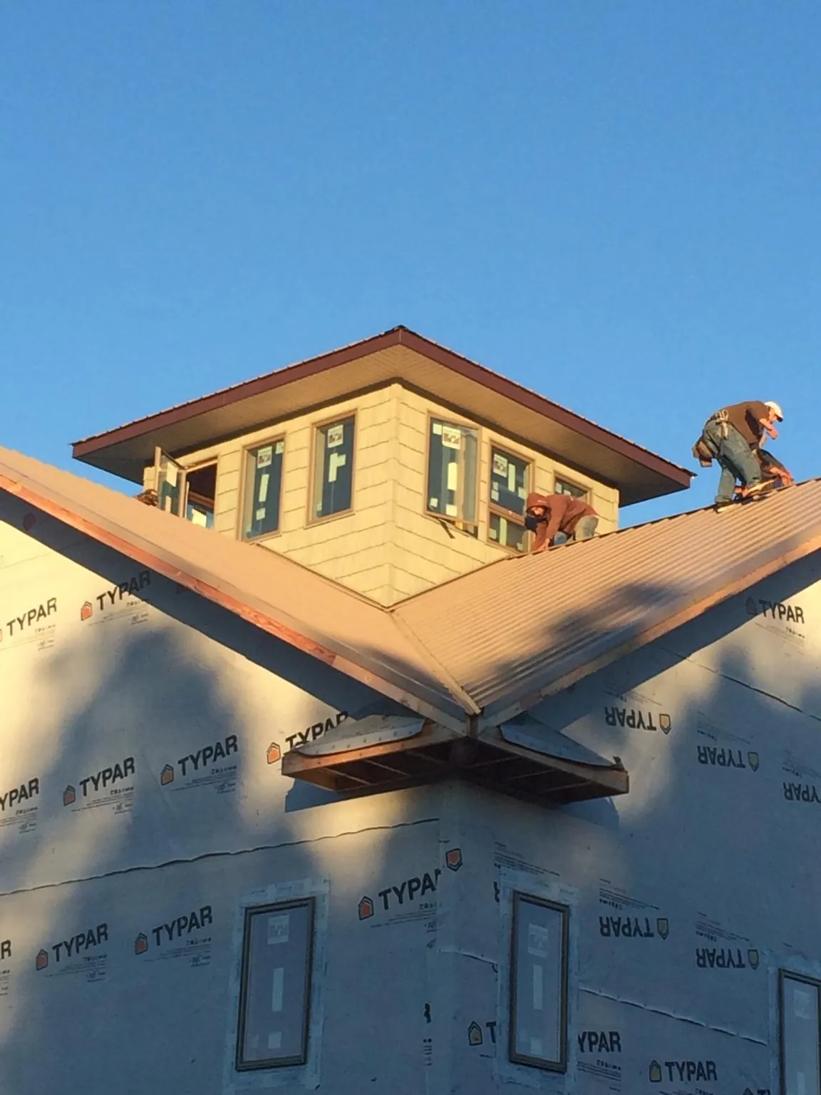 Roofers working around a rooftop cupola on a new metal roof at sunset — Roof Waterproofing in Soledad by Roofing Brothers